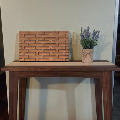 Wooden Cutting board with a woven pattern to look like it's made from wicker. Sitting on top of a walnut console table.